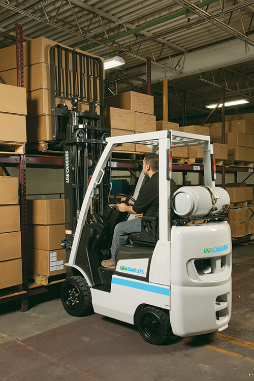 unicarriers forklift in warehouse lifting box onto racking